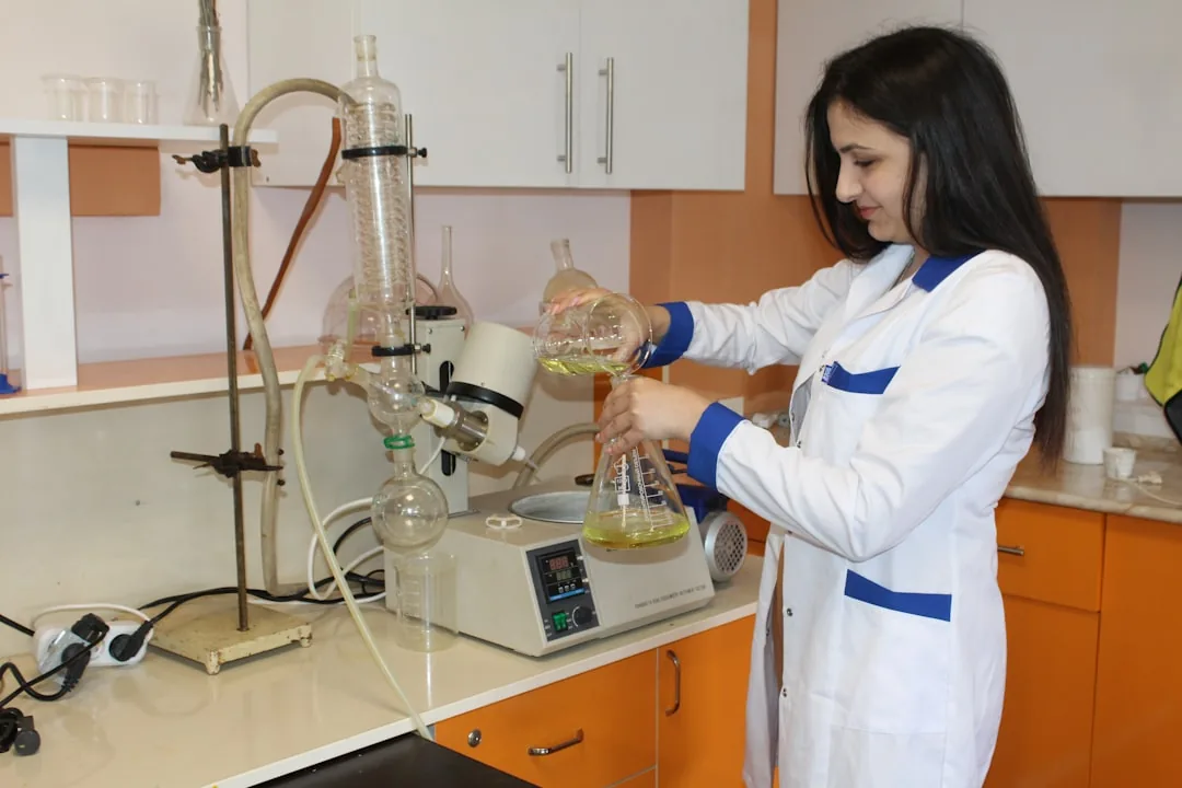 Scientist in a research laboratory pouring liquid into glassware